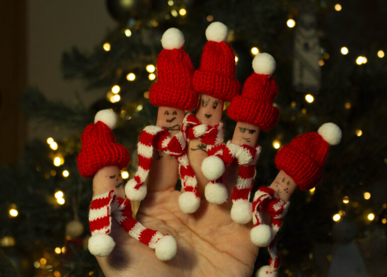 Een eigen gemaakte kerstmis foto met een hand en kerstmishoedjes en gezichtjes